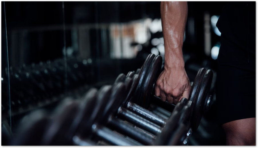 Svettig hand som greppar en tung hantel på ett gym