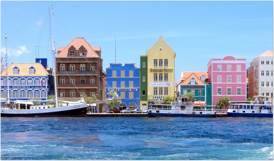 Färgglada kolonialbyggnader vid vattnet i Willemstad på Curacao med båtar i hamnen