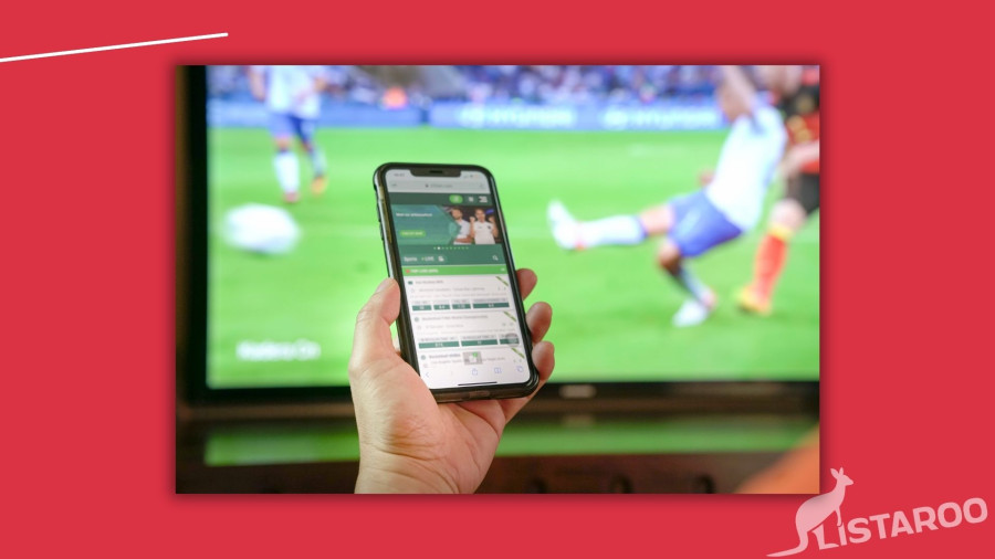 Person som bettar framför en tv med hjälp av sin mobil